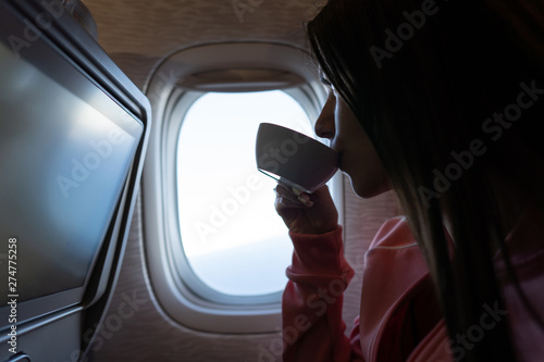 Young woman drinking a coffee in airplane