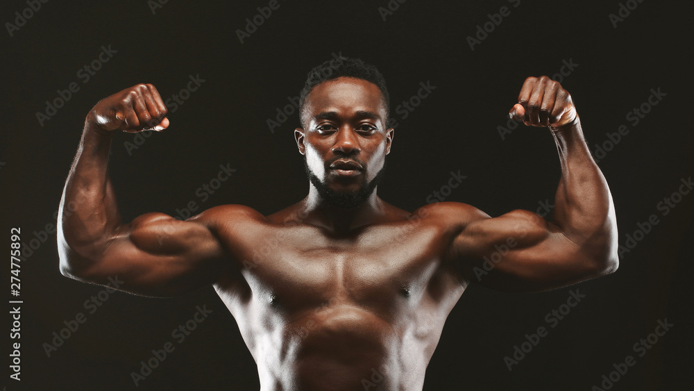 Obraz premium Black athlete flexing muscles, demonstrating strong biceps