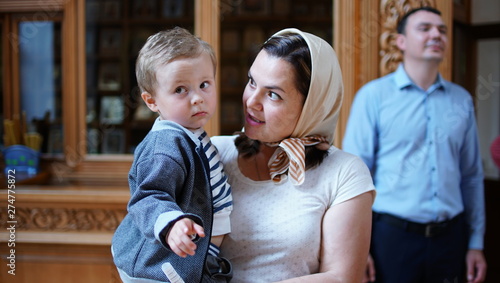 Fotografija Little boy in armes of women with headscarf in Orthodox Church.