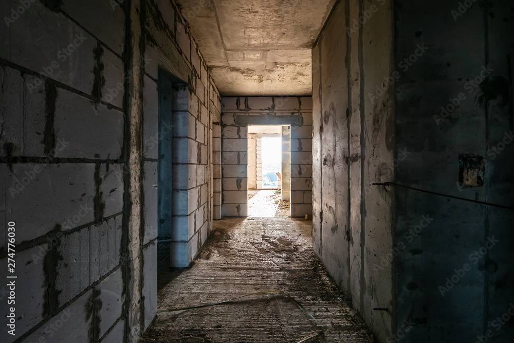 Unfinished corridor in interior of construction site inside of new modern residential building Unfinished corridor in interior of construction site inside of new modern residential building