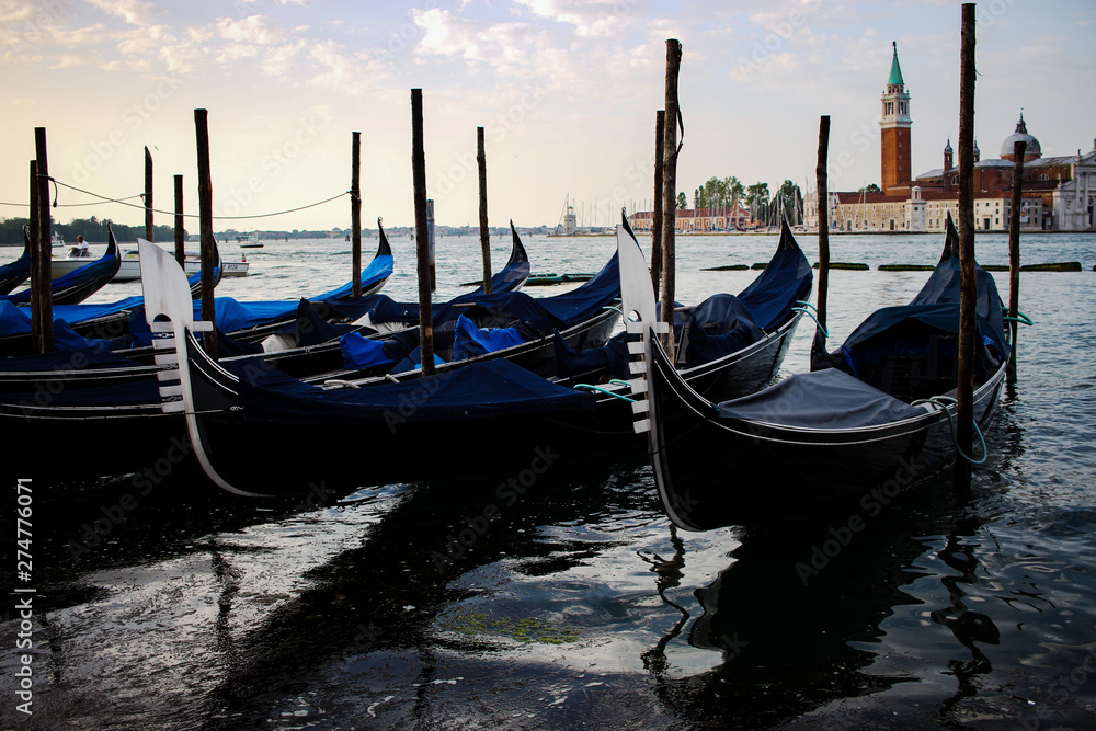 A row of gondolas lined up by the dock in Venice, Italy