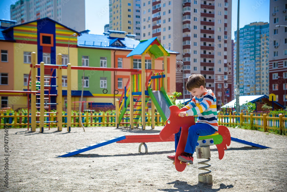 Cute little boy having fun on outdoor playground. Spring/summer/autumn active sport leisure for kids. Outdoors wooden equipment for children game