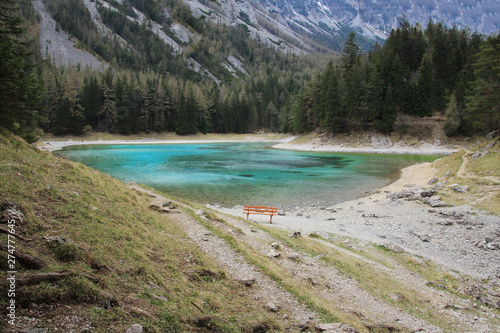 Turquoise lake in Austria. Bench is near the quiet lake. 
