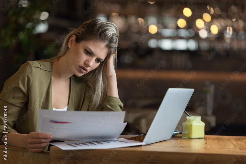 Displeased businesswoman reading problematic reports in a cafe Displeased businesswoman reading problematic reports in a cafe