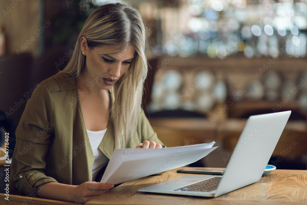 Businesswoman reading documents while working in a cafe Businesswoman reading documents while working in a cafe