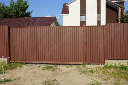 long private closed metal gate of brown color on the street © butus