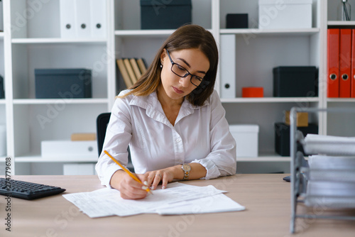Young beautiful businesswoman work with documents fill in blank