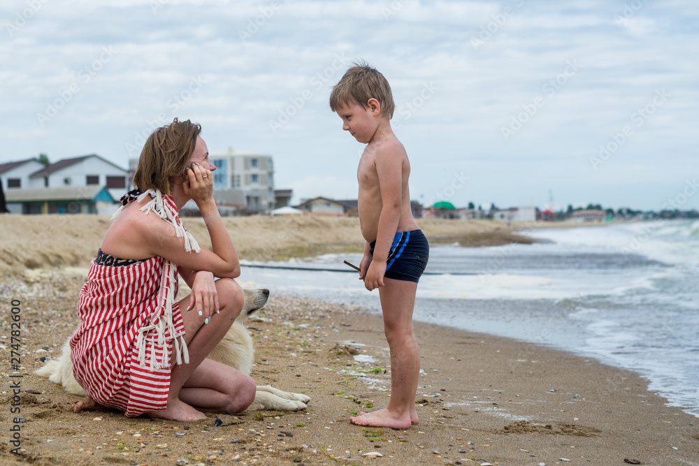Mum with the small son and a dog have a rest on the seashore, ocean. Mum with the small son and a dog have a rest on the seashore, ocean.