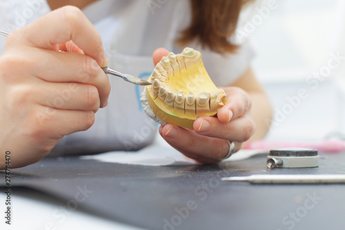 dental technician shaping a prosthesis tooth