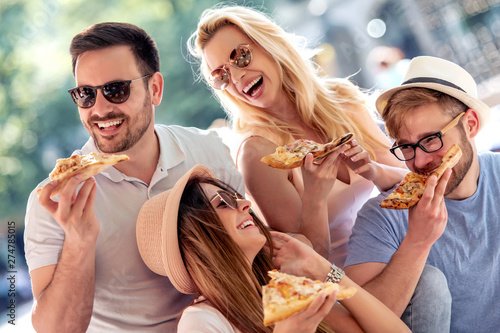 Group of friends eat pizza outdoors