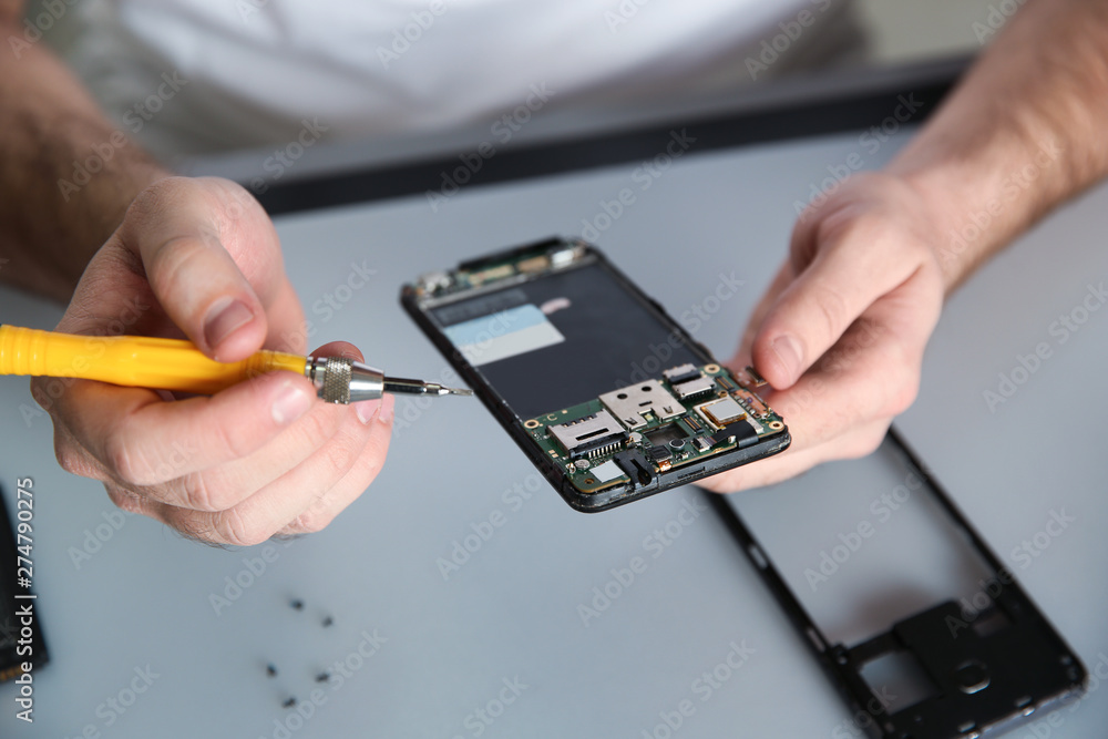 Technician repairing mobile phone at table, closeup Technician repairing mobile phone at table, closeup