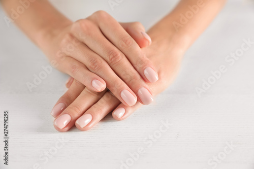 Closeup view of woman with smooth hands and manicure at table, space for text. Spa treatment
