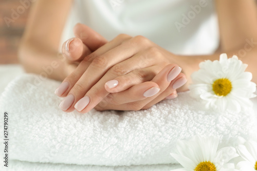 Woman with smooth hands and flowers on towel  closeup. Spa treatment