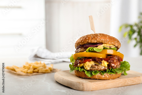Fototapeta Board with tasty burger on table. Space for text
