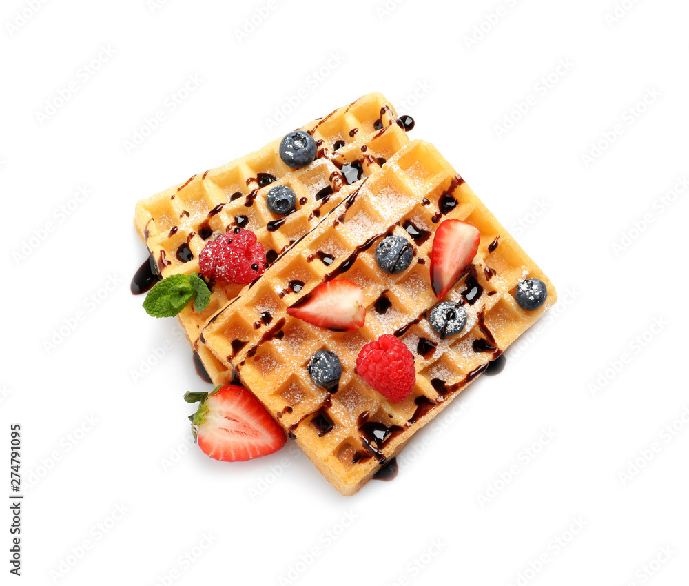 Yummy waffles with berries and chocolate syrup on white background, top view