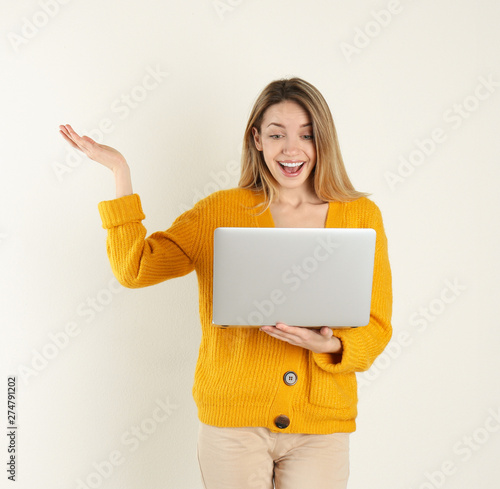 Portrait of young woman in casual outfit with laptop on light background. Space for text