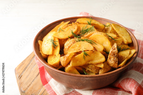 Bowl of delicious oven baked potatoes with dill on table, closeup