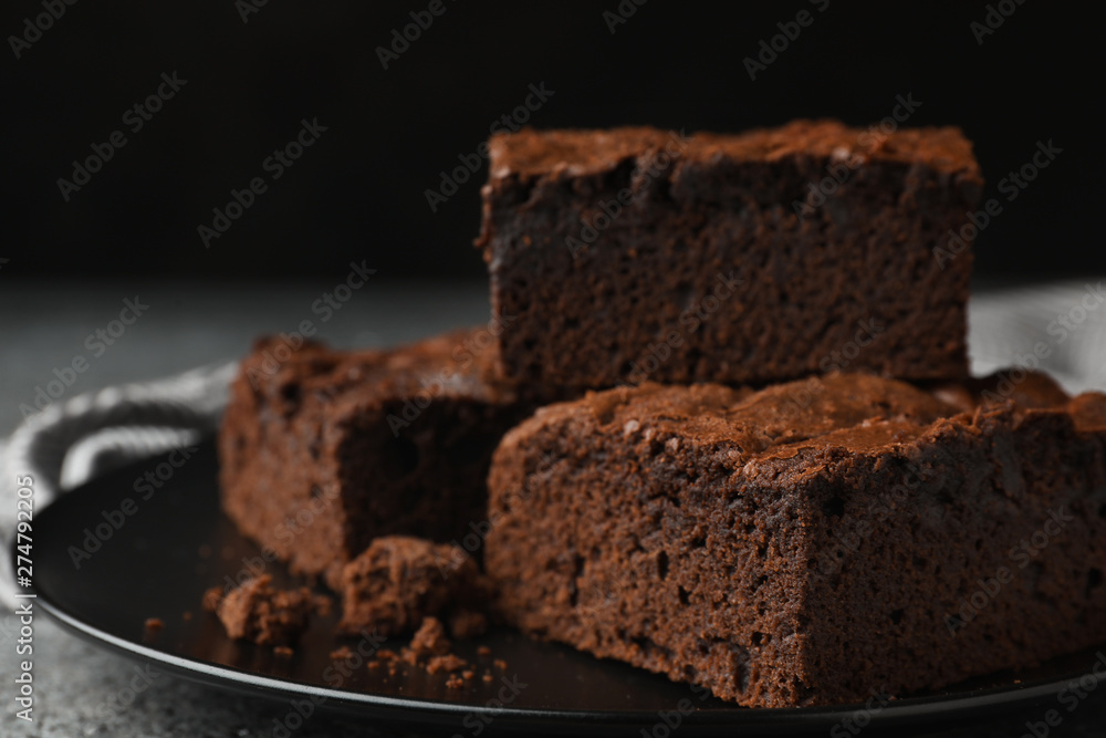 Plate with fresh brownies on grey table against black background, space for text. Delicious chocolate pie Plate with fresh brownies on grey table against black background, space for text. Delicious chocolate pie