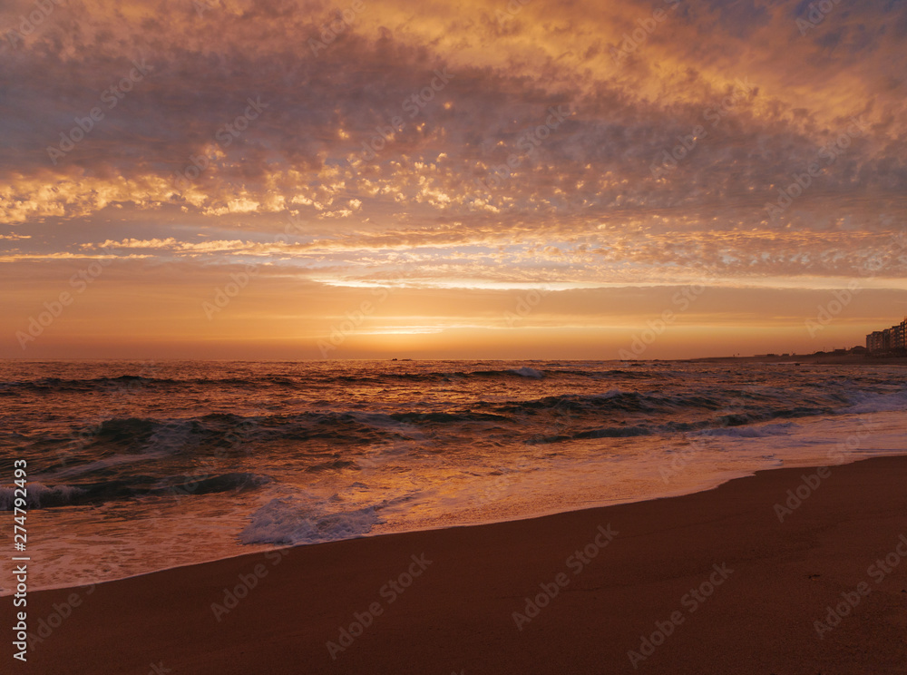 Wide angle view over beach at sunset in Portugal with beautiful clouds