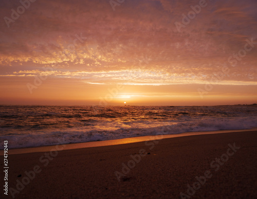 Beautiful vivid sky at sunset on the beach as waves break on shore