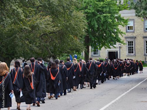 Procession of univesrsity students walking outdoors toward their graduation ceremony