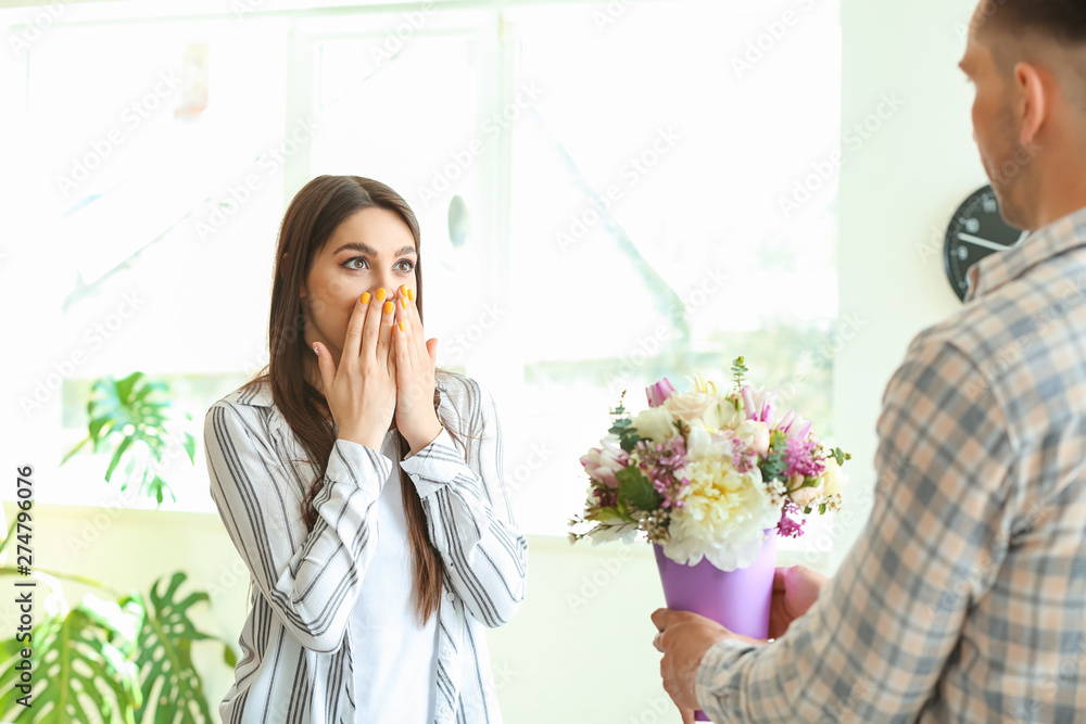 Husband greeting his wife with bouquet of flowers at home Husband greeting his wife with bouquet of flowers at home