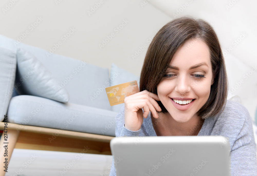 Young woman with credit card and tablet computer shopping online at home Young woman with credit card and tablet computer shopping online at home