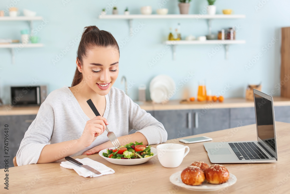 Beautiful woman eating at table in kitchen