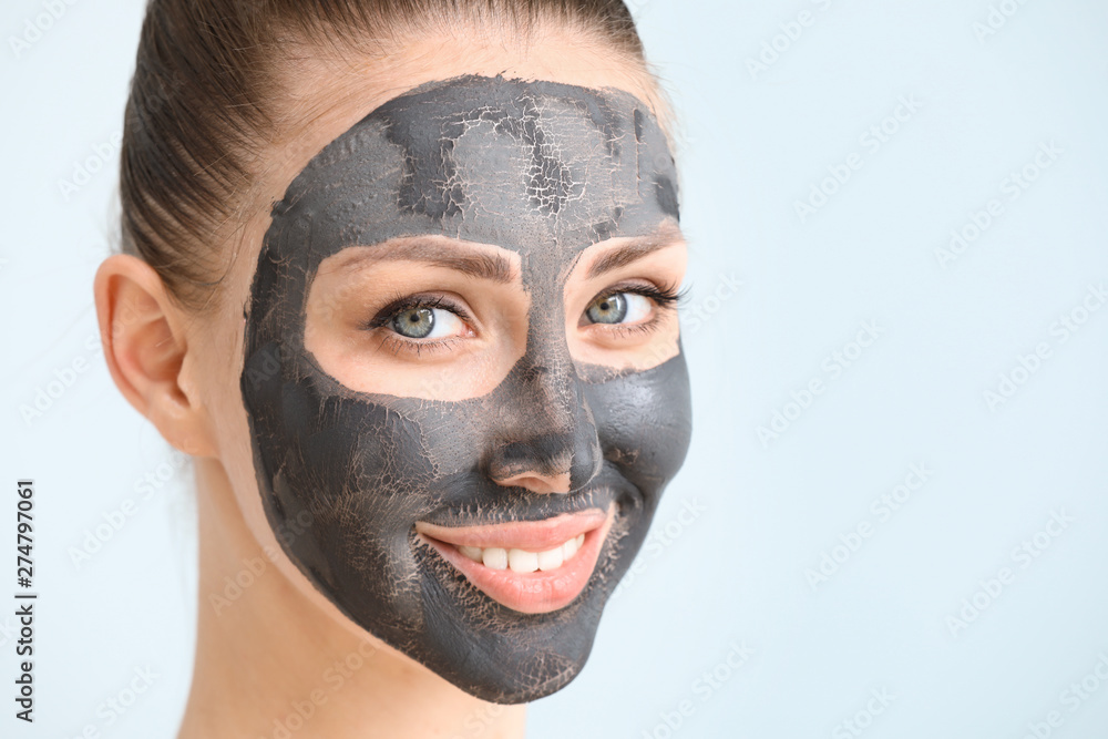 Beautiful young woman with facial mask on color background Beautiful young woman with facial mask on color background