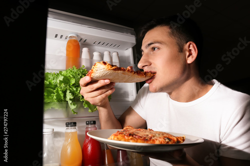 Young man eating pizza near...