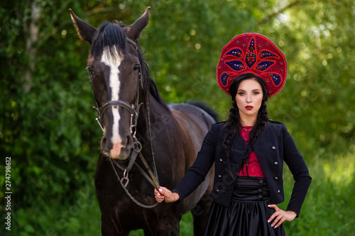 Gorgeous Caucasian Model in Kokoshnik Holding Thoroughbred Horse Against Nature Background Outdoors.