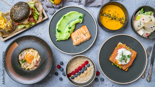 Foodset on table. poached egg with salmon and avocado on a white plate, burger, grilled salmon with mashed beens, pumpkin soup, carbonara and oatmeal porridge top view food.