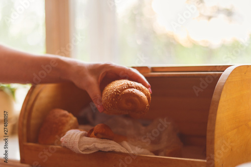 woman taking a bread loaf from a bread box in the kitchen at home photo