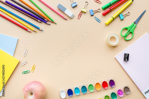 School supplies stationery, colour pencils, paints, paper on pastel orange background, back to school concept with free copy space for text, modern elementary education. flat lay, top view, mockup.