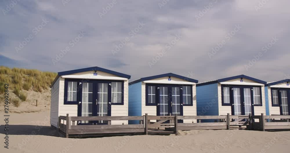 Small wooden beach houses or bungalows at a North Sea beach with dunes in the background. Small wooden beach houses or bungalows at a North Sea beach with dunes in the background.
