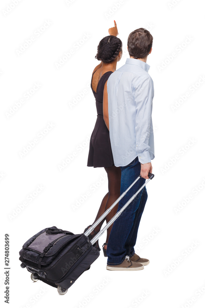 Back view of pointing interracial going couple with suitcase. Back view of pointing interracial going couple with suitcase.