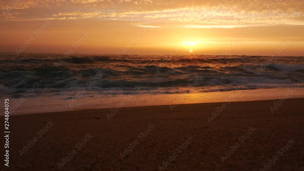 Low angle view over shoreline on beach at sunset as sun dips below horizon Low angle view over shoreline on beach at sunset as sun dips below horizon