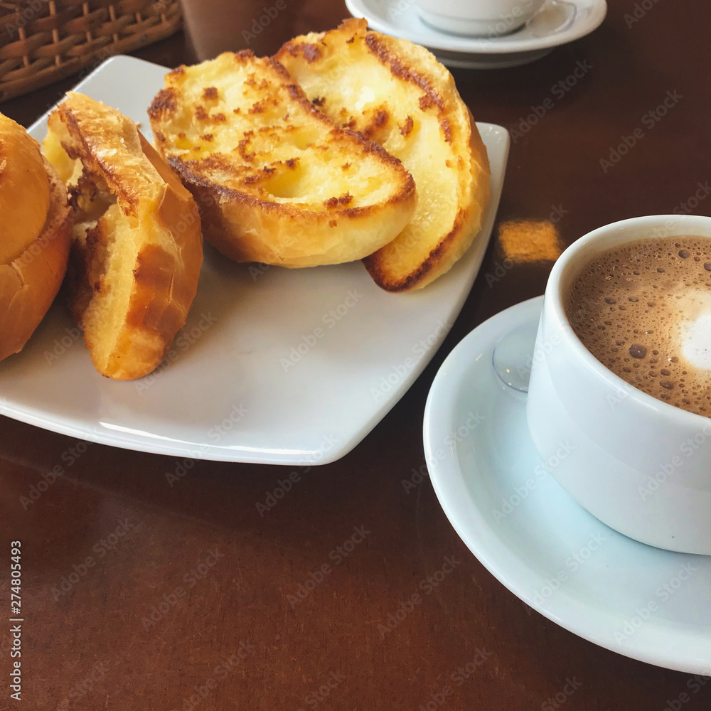 Brazilian breakfast. Capuccino cup and toasted bread with butter background. Brazilian breakfast. Capuccino cup and toasted bread with butter background.