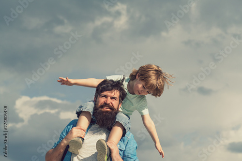 Father and son. Family Time. Daddy and child son. Happy kid playing - airplane. Portrait of happy father giving son piggyback ride on his shoulders and looking up.