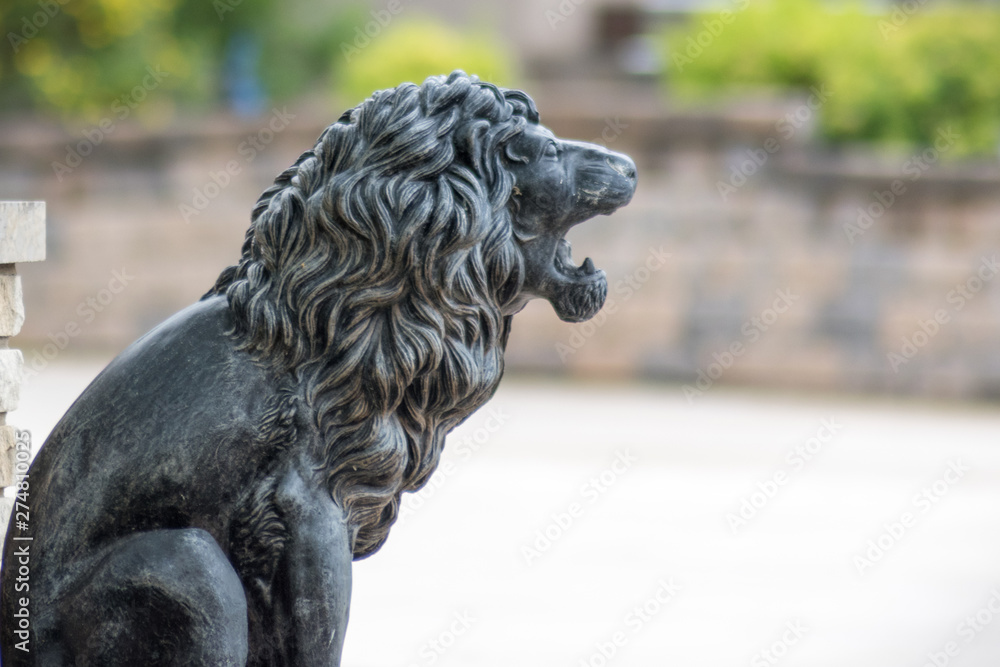 A stone loin sculpture sitting on ground A stone loin sculpture sitting on ground