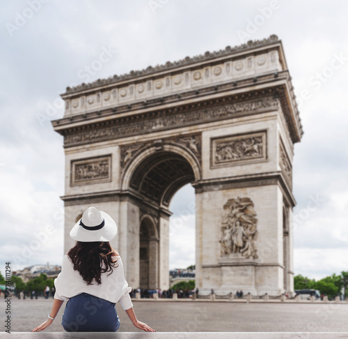 Photography Young traveler woman in white hat looking at Arc de Triomphe, famous landmark an