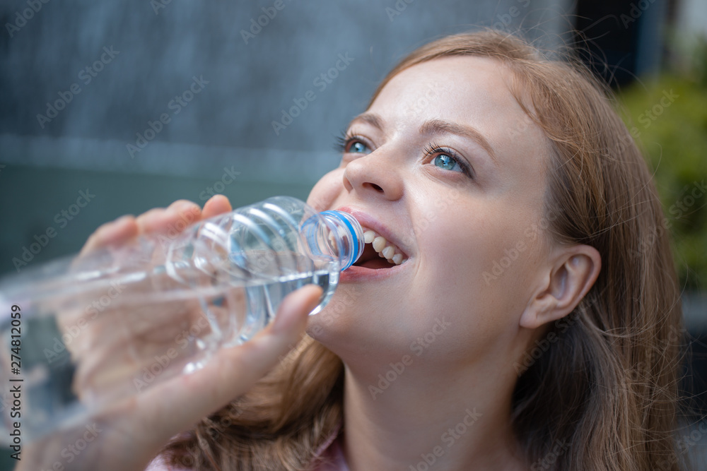Closeup portrait of young caucasian woman drinking water from a plastic bottle, smiling Closeup portrait of young caucasian woman drinking water from a plastic bottle, smiling