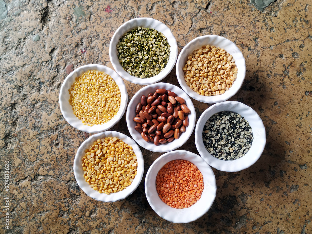 Uncooked pulses,grains and seeds in White bowls over stone background. selective focus Uncooked pulses,grains and seeds in White bowls over stone background. selective focus