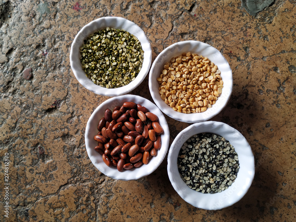 Uncooked pulses,grains and seeds in White bowls over stone background. selective focus Uncooked pulses,grains and seeds in White bowls over stone background. selective focus