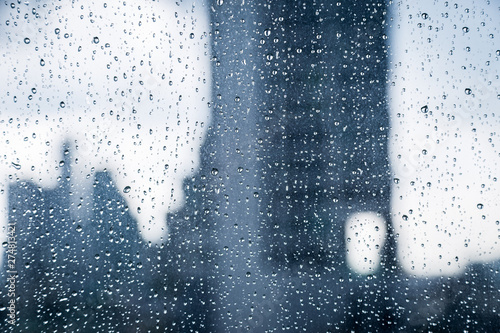 Abstract image of Rain drops on the dirty glass windows with modern office building