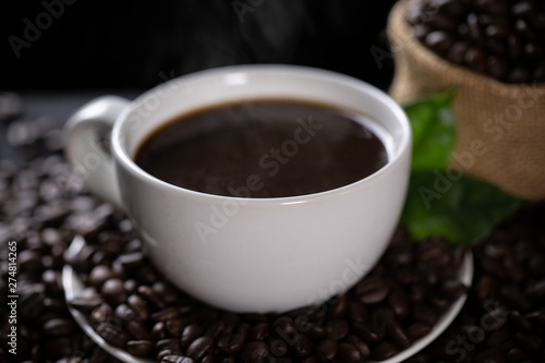 Hot coffee cup with coffee beans on the wooden table
