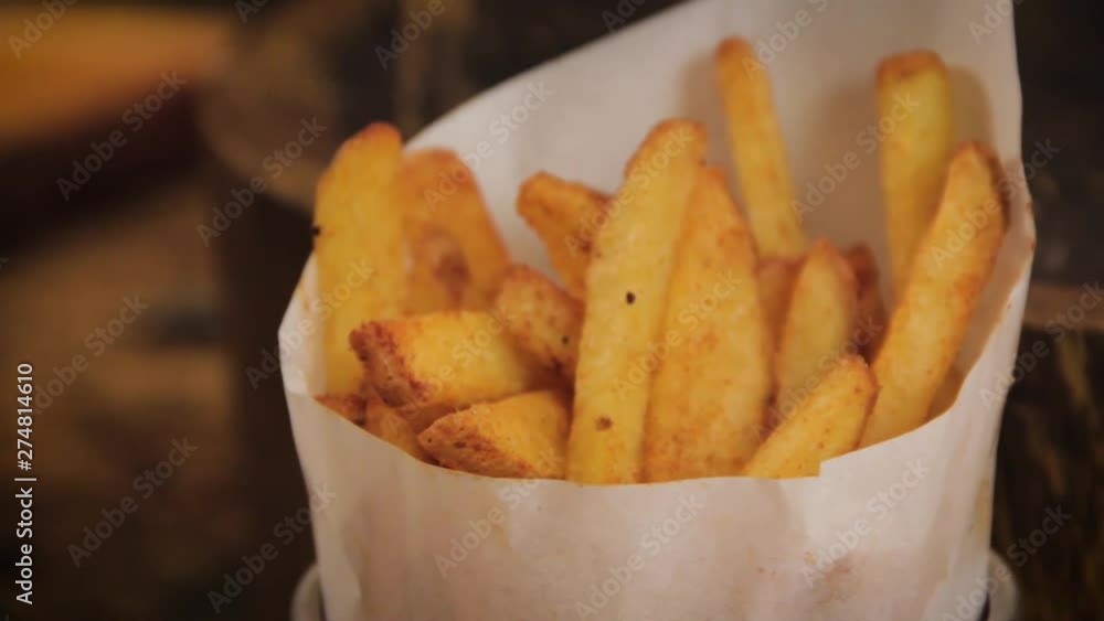 Homemade, crispy and delicious rustic french fries displayed in a metal cup with paper wrap - slider motion, close up Homemade, crispy and delicious rustic french fries displayed in a metal cup with paper wrap - slider motion, close up