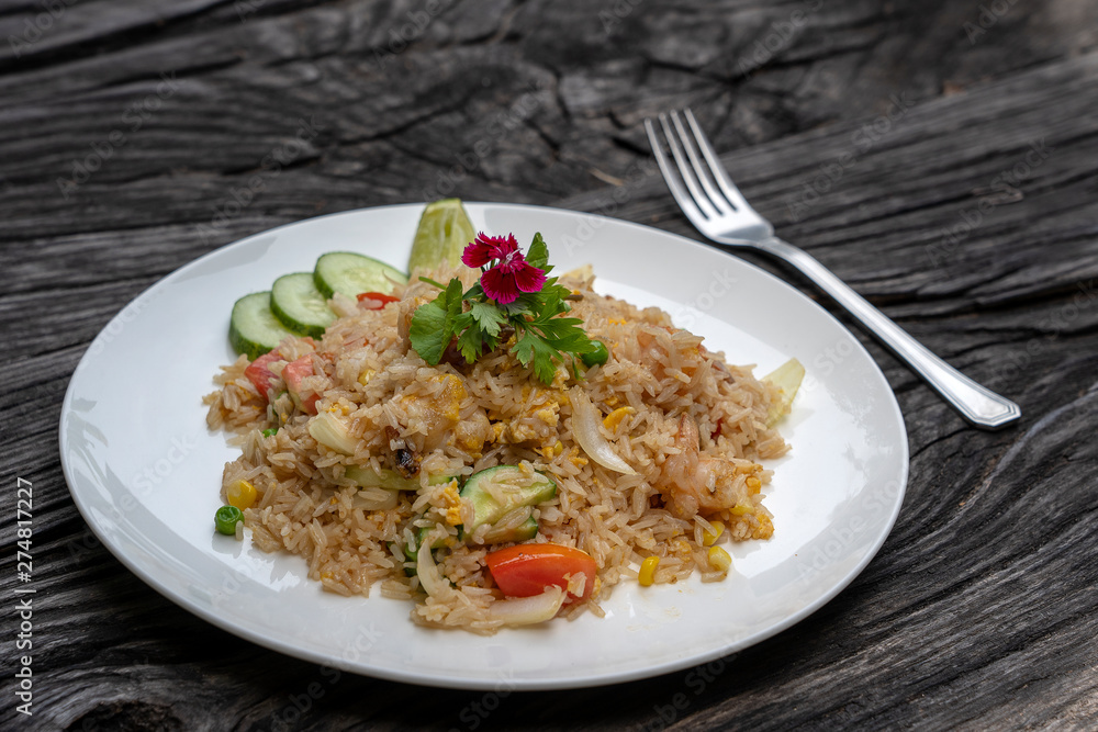 Fried rice with shrimps and vegetables in a white dish on an old wooden table, close up . Thai food , Thai cuisine Fried rice with shrimps and vegetables in a white dish on an old wooden table, close up . Thai food , Thai cuisine