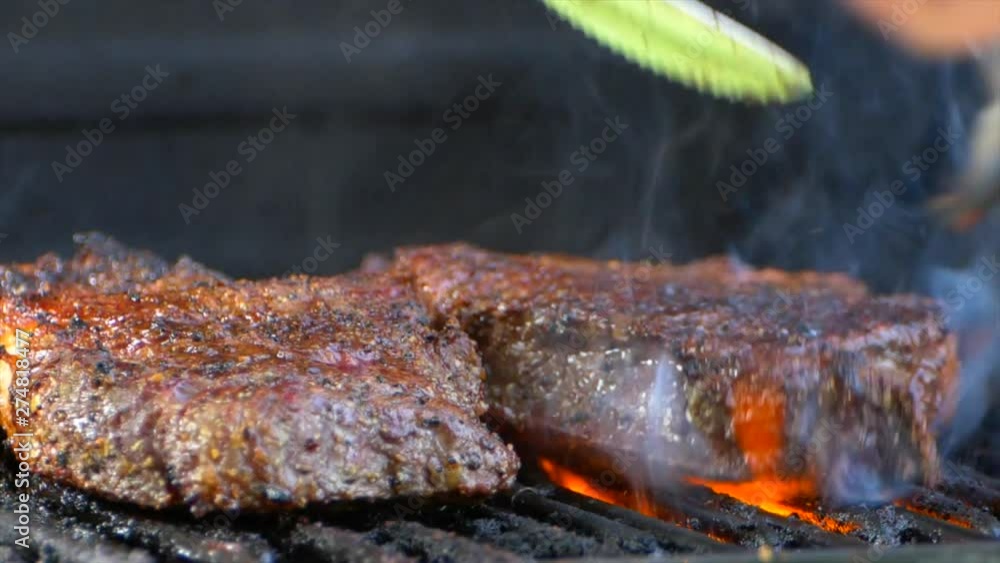 The best shot of a fork turns a nearly cooked juicy rib eye steak on a grill and orange flames shoot up out from underneath it. The best shot of a fork turns a nearly cooked juicy rib eye steak on a grill and orange flames shoot up out from underneath it.