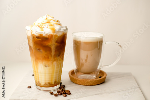 Ice coffee in the glass topped whipping cream with coffee beans. Cold summer drink on wooden background and copy space. Advertising for caramel mocha and chocolate beverage for the cafe.